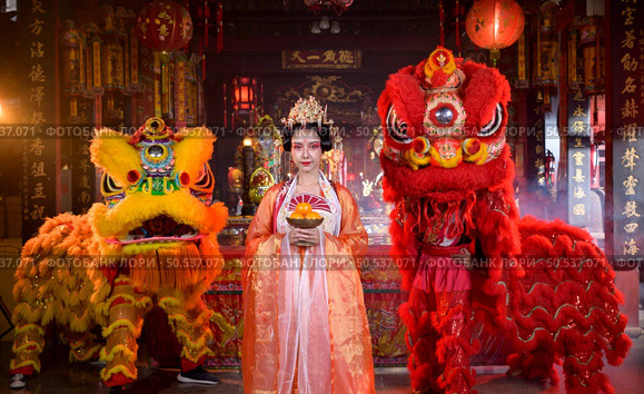 Chinese woman with yellow and red lions It is considered to enhance the prosperity for oneself on the occasion of the Chinese New Year festival every year and in Chinese, it means prosperous, fortunate, happy, prosperous. Стоковое фото, агентство Ingram Publishing / Фотобанк Лори