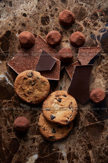 Chocolate chip cookies and different chocolate on cocoa powder and dark marble background. Chocolate chip cookies and chocolates. Стоковое фото, агентство Ingram Publishing / Фотобанк Лори