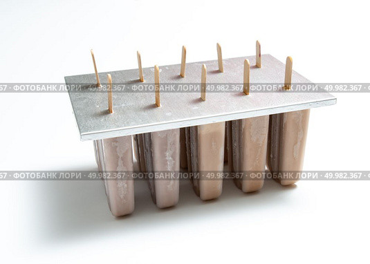 Chocolate ice cream Ice lollies in plastic molds with shadows on white background with space for text. Cooling summer dessert. Homemade organic chocolate ice cream lolly in plastic molds with a reflection of shadows on a white background with copy space. Стоковое фото, агентство Ingram Publishing / Фотобанк Лори