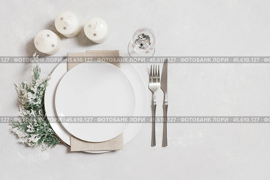 Christmas serving with empty white plate, candles and silverware on white background. Beautiful New Year table setting with copy space. Top view, flat lay. Стоковое фото, фотограф Марина Багрова / Фотобанк Лори