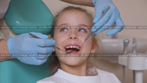Close up dentist, doctor examines the oral cavity of a little girl, uses a mouth mirror, baby teeth close-up. Concept of pediatric dentistry, dental treatment. Slow motion footage. Стоковое видео, видеограф Ирина Михайличенко / Фотобанк Лори