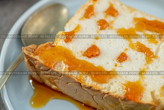 Close-up of a delicious slice of molotof, a traditional caramelized egg white pudding, generously drizzled with sweet syrup on a light blue plate with a silver spoon. Стоковое фото, агентство Ingram Publishing / Фотобанк Лори