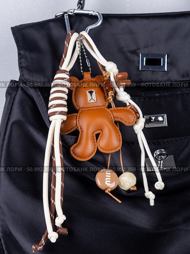 Close-up of a stylish leather bag accessory featuring a detailed leather bear charm no black  bag. Стоковое фото, фотограф Виталий Сова / Фотобанк Лори