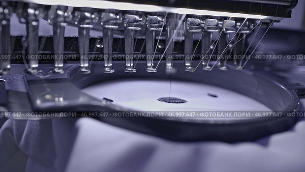 Close up of industrial loom creating embroidery on white fabric. Стоковое фото, фотограф David Kashakhi / Фотобанк Лори