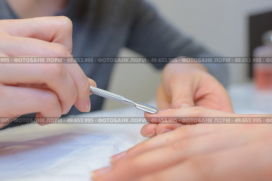 close up of professional manicurist using cuticle pusher doing manicure. Стоковое фото, агентство Ingram Publishing / Фотобанк Лори