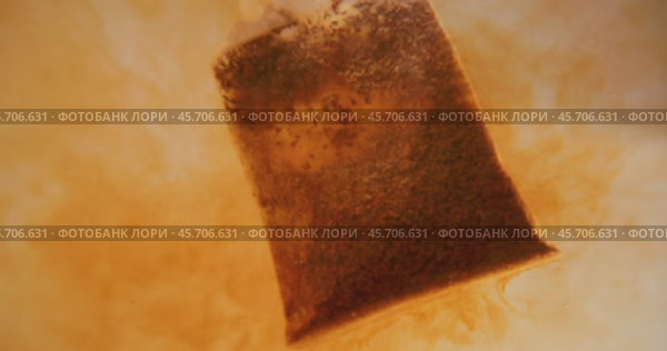 Close up of tea bag diffusing in a clear glass. Macro slow motion shot of the process of brewing herbal. Стоковое видео, видеограф Андрей Армягов / Фотобанк Лори