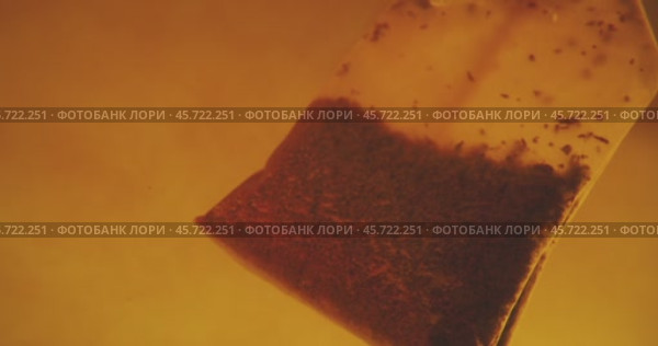 Close up of tea bag diffusing in a clear glass. Macro slow motion shot of the process of brewing herbal. Стоковое видео, видеограф Андрей Армягов / Фотобанк Лори