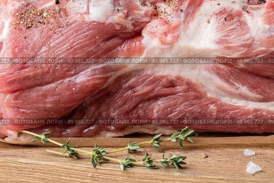 Close up photo of raw meat. Macro of pork neck with herbs and green thyme on wooden board. Close up photo of raw meat. Pork neck with herbs. Стоковое фото, агентство Ingram Publishing / Фотобанк Лори