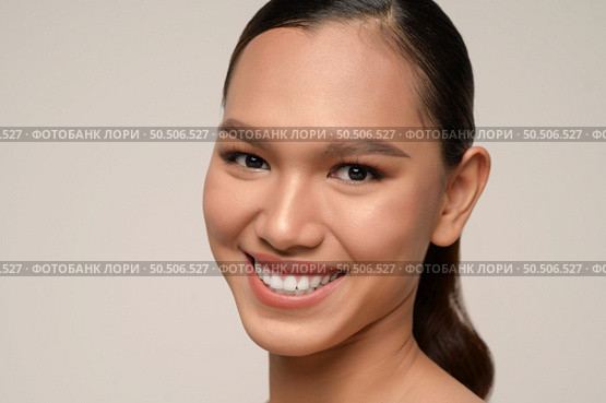 Close up, portrait of beautiful woman model with fresh daily make-up and toothy smile with beautiful face on gray background in studio, copy space. Стоковое фото, агентство Ingram Publishing / Фотобанк Лори