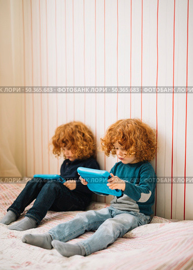 close up twins with red headed hair looking digital tablet. Стоковое фото, агентство Ingram Publishing / Фотобанк Лори