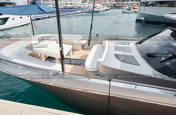 Close-up view of a relaxation area on the open teak deck of an expensive motorboat at sunny day, Monaco yacht show, large boat exhibition, wealth life, table and chairs. Стоковое фото, фотограф Vladimir Drozdin / Фотобанк Лори