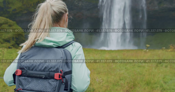 Closeup of female traveler back with backpack loking to Beautiful Seljalandsfoss waterfall Iceland. Стоковое видео, видеограф Igor Tichonow / Фотобанк Лори