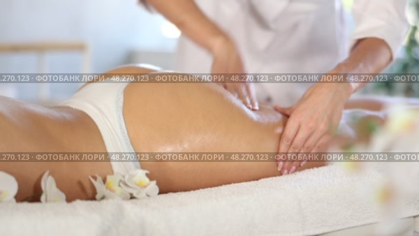 Closeup of hands of professional masseuse performing anti-cellulite massage on buttocks and thighs of young female client at spa center. Стоковое видео, видеограф Яков Филимонов / Фотобанк Лори