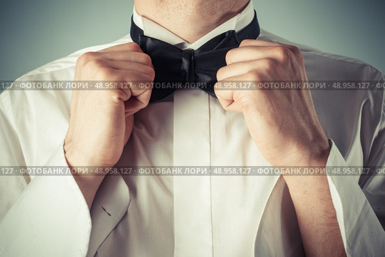 Closeup on a young man as he is tying a bow tie. Стоковое фото, агентство Ingram Publishing / Фотобанк Лори