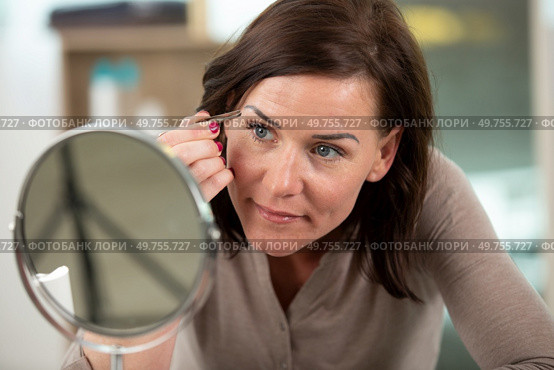 closeup on young woman tweezing eyebrows. Стоковое фото, агентство Ingram Publishing / Фотобанк Лори