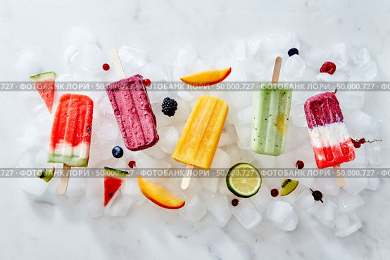 Collection of colorful tasty homemade ice cream lolly on a stick with juicy berries and pieces of various fruits on ice cubes. Flat lay. Different ice cream on a stick and different pieces of fruit and berries on ice cubes. Flat lay. Стоковое фото, агентство Ingram Publishing / Фотобанк Лори