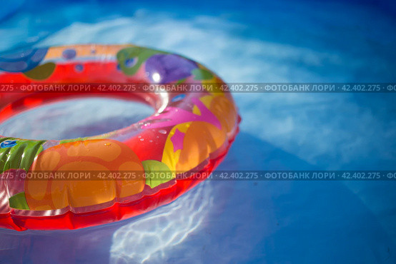 Colorful ring floating in a refreshing blue swimming pool. Стоковое фото, фотограф Александра Баранова / Фотобанк Лори