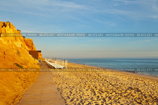 Comfortable Falesia beach with wooden walkways and sun beds at the terracotta rocks on the shallow sandy seashore. Vilamoura, Algarve, Portugal. Natural background Summer holiday by the sea (2012 год). Стоковое фото, фотограф Виктория Катьянова / Фотобанк Лори