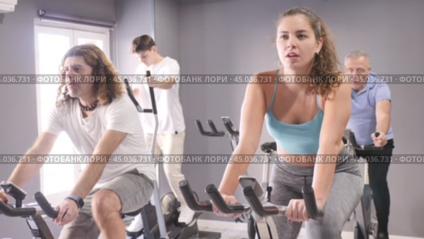 Concentrated young fit girl working out on stationary bicycle in gym. Healthy active lifestyle concept. Стоковое видео, видеограф Яков Филимонов / Фотобанк Лори