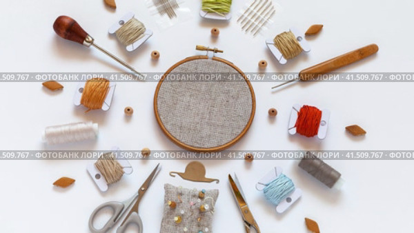Concept of hand embroidery. Video of circular composition of accessories for cross stitch: hoop with canvas, scissors, set of needles, beads, skeins of cotton threads in natural colors, pins. Flat lay, close-up, top view. Стоковое видео, видеограф Виктория Катьянова / Фотобанк Лори