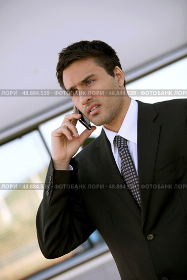 Concerned businessman holding cellphone. Стоковое фото, агентство Ingram Publishing / Фотобанк Лори