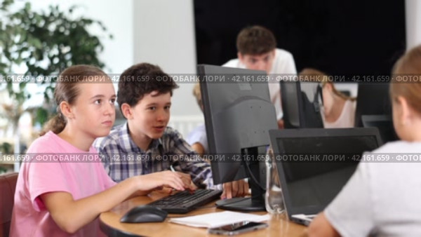 Concerned preteen girl and boy working together on computer in IT training room. Стоковое видео, видеограф Яков Филимонов / Фотобанк Лори