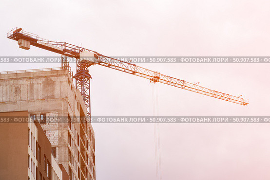 Construction crane towers over building under construction. Стоковое фото, фотограф Антон Вахрушев / Фотобанк Лори