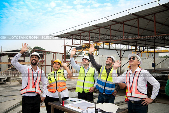 Construction engineers, architects, and foremen form a group. Participate in a meeting to plan new construction projects. Cheers to express happiness that the event was successfully accomplished. Стоковое фото, агентство Ingram Publishing / Фотобанк Лори