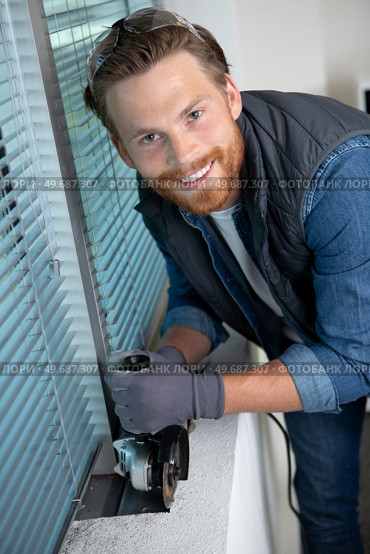 construction worker cutting concrete wall by using handheld circular saw. Стоковое фото, агентство Ingram Publishing / Фотобанк Лори