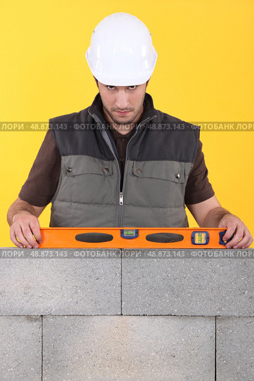 Construction worker measuring an angle with a spirit level. Стоковое фото, агентство Ingram Publishing / Фотобанк Лори
