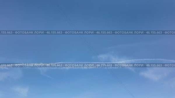 Contrails creating patterns in the clear blue sky above a tranquil landscape during midday. Timelapse. Стоковое видео, видеограф Наталия Попова / Фотобанк Лори