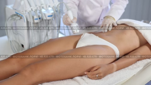 Cosmetologist administering ice hammer therapy to tighten skin and promoting elasticity on female client thighs at aesthetic medicine clinic. Modern hardware body care procedure. Стоковое видео, видеограф Яков Филимонов / Фотобанк Лори