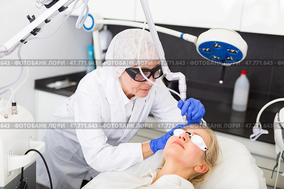 Cosmetologist making laser mole removal procedure for young woman. Стоковое фото, фотограф Яков Филимонов / Фотобанк Лори