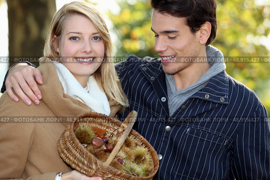 Couple collecting chestnuts in the woods. Стоковое фото, агентство Ingram Publishing / Фотобанк Лори