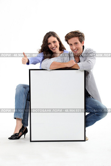 Couple crouching by empty frame. Стоковое фото, агентство Ingram Publishing / Фотобанк Лори