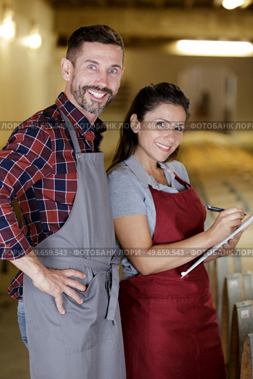 couple in wine cellar writing information on clipboard. Стоковое фото, агентство Ingram Publishing / Фотобанк Лори