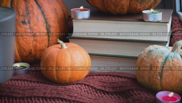 Cozy Hygge scene with sweater and candles. Orange pumpkins and cup of tea ore coffee. Halloween concept, cozy home, aromatherapy. Стоковое видео, видеограф Марина Демидюк / Фотобанк Лори