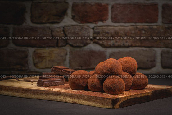 Craft chocolate truffles on wooden board with cocoa powder. Стоковое фото, агентство Ingram Publishing / Фотобанк Лори
