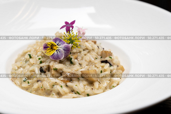 Creamy cheese risotto with mushroom and truffle oil decorate with yellow and purple flower. International italian gourmet cuisine a la carte in buffet live station. Using for food and drink industry.. Risotto. Стоковое фото, агентство Ingram Publishing / Фотобанк Лори