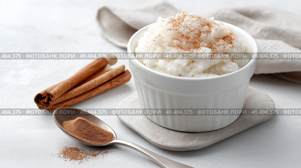 Creamy rice pudding served with cinnamon on a light surface. Сливочный рисовый пудинг с корицей на светлой поверхности. Стоковое AI-изображение, AI-художник Katsiaryna Repich / Фотобанк Лори