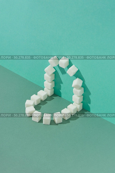 Creative corner geometric composition from sweet pressed refined sugar blocks on a duotone background in green colors with copy space.. Corner geometric composition from sweet refined sugar cubes. Стоковое фото, агентство Ingram Publishing / Фотобанк Лори