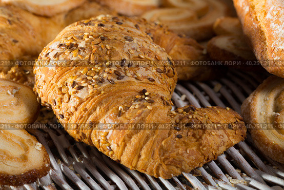 Croissant on rattan mat with other bakery goods. Стоковое фото, фотограф Яков Филимонов / Фотобанк Лори