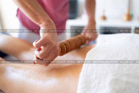 Crop anonymous osteopath performing wood therapy message on leg of unrecognizable female patient lying on bed during physiotherapy session in clinic. Crop osteopath doing wood therapy massage on client. Стоковое фото, агентство Ingram Publishing / Фотобанк Лори