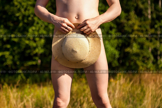 Crop photo of naked shy man nudist covering summer hat on greenery nature outdoors, close up. Confused nude young male standing, natural idyllic lifestyle. Nudism naturism concept. Copy ad text space. Стоковое фото, фотограф Aleksandr Golubev / Фотобанк Лори