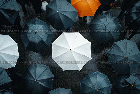 Crowded city street filled with umbrellas during a rainy day with one striking white umbrella in focus. Стоковое AI-изображение, AI-художник Михаил Коханчиков / Фотобанк Лори