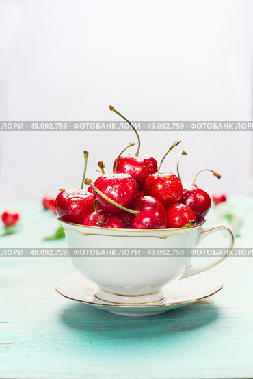 Cup full of ripe sweet cherries on light background, close up. Summer fruits and berries concept. Стоковое фото, агентство Ingram Publishing / Фотобанк Лори