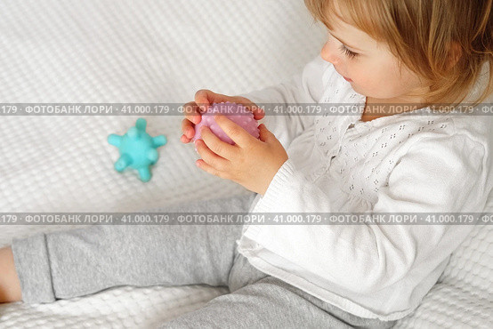 Cute baby girl playing tactile knobby balls. Young child hand plays sensory massage ball. Enhance the cognitive, physical process. Brain development. Support for Children with ADHD, autism, fidgeting. Стоковое фото, фотограф Марина Демидюк / Фотобанк Лори