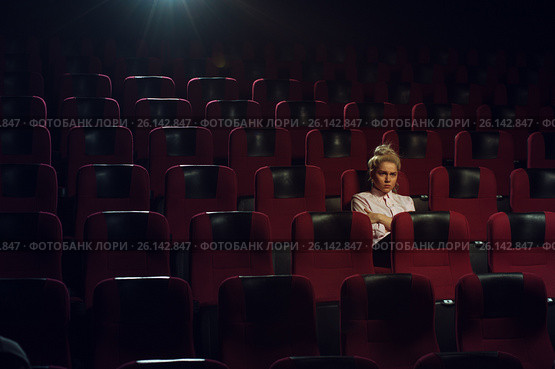 Cute blonde girl watching movie in cinema theater. Стоковое фото, фотограф Pavel Biryukov / Фотобанк Лори