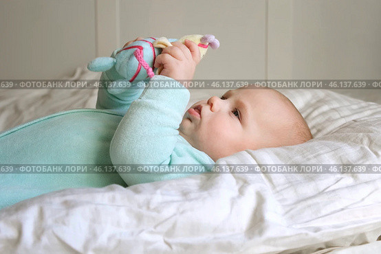 Cute Newborn Baby Lying on the Back and Plays with Colorful Toys. Little Three Month Child Takes a Toy. Portrait of Playful Neonate Toddler. Concept of Childhood, New Life, Baby Care. Top View. Стоковое фото, фотограф Марина Демидюк / Фотобанк Лори