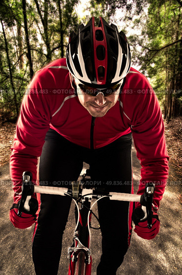 Cyclist on road bike through a forest. Стоковое фото, агентство Ingram Publishing / Фотобанк Лори